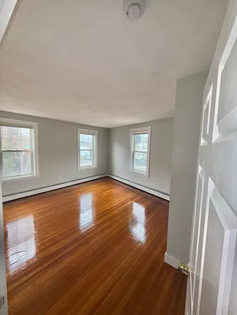 a view of empty room with wooden floor and fan