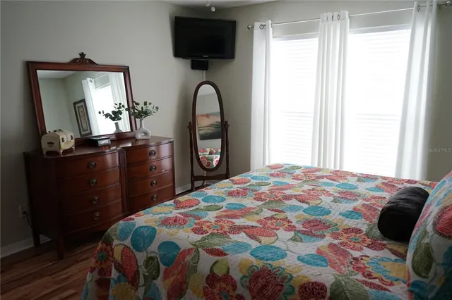 a bedroom with a bed and a flat tv screen on dresser