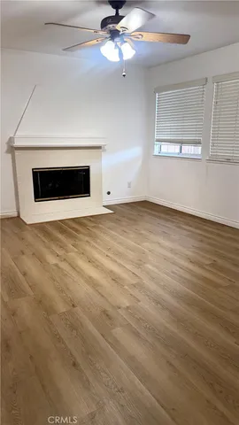 an empty room with wooden floor fan and windows