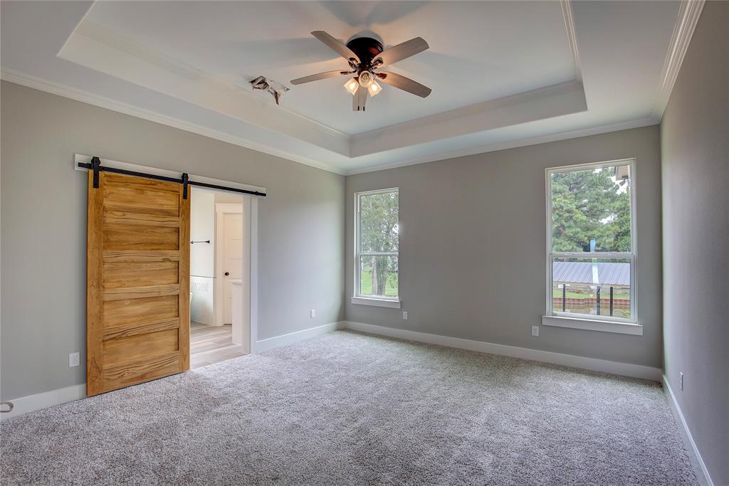 405 Door Key Ranch Road Trinidad, TX 75163 - Photo 18 of 28 Unfurnished bedroom featuring carpet, a barn door, ceiling fan, a raised ceiling, and ornamental molding