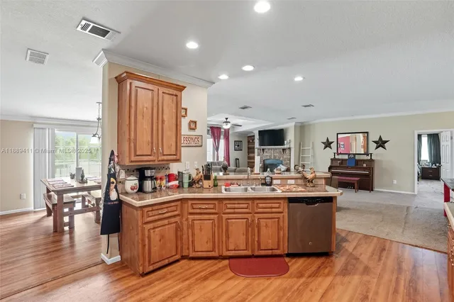 a kitchen with stainless steel appliances granite countertop a stove a sink dishwasher and a microwave with wooden floor