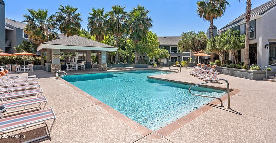 445 South Dobson Road, Unit A2 Mesa, AZ 85202 - Photo 6 of 7 a view of a swimming pool with a table and chairs under an umbrella