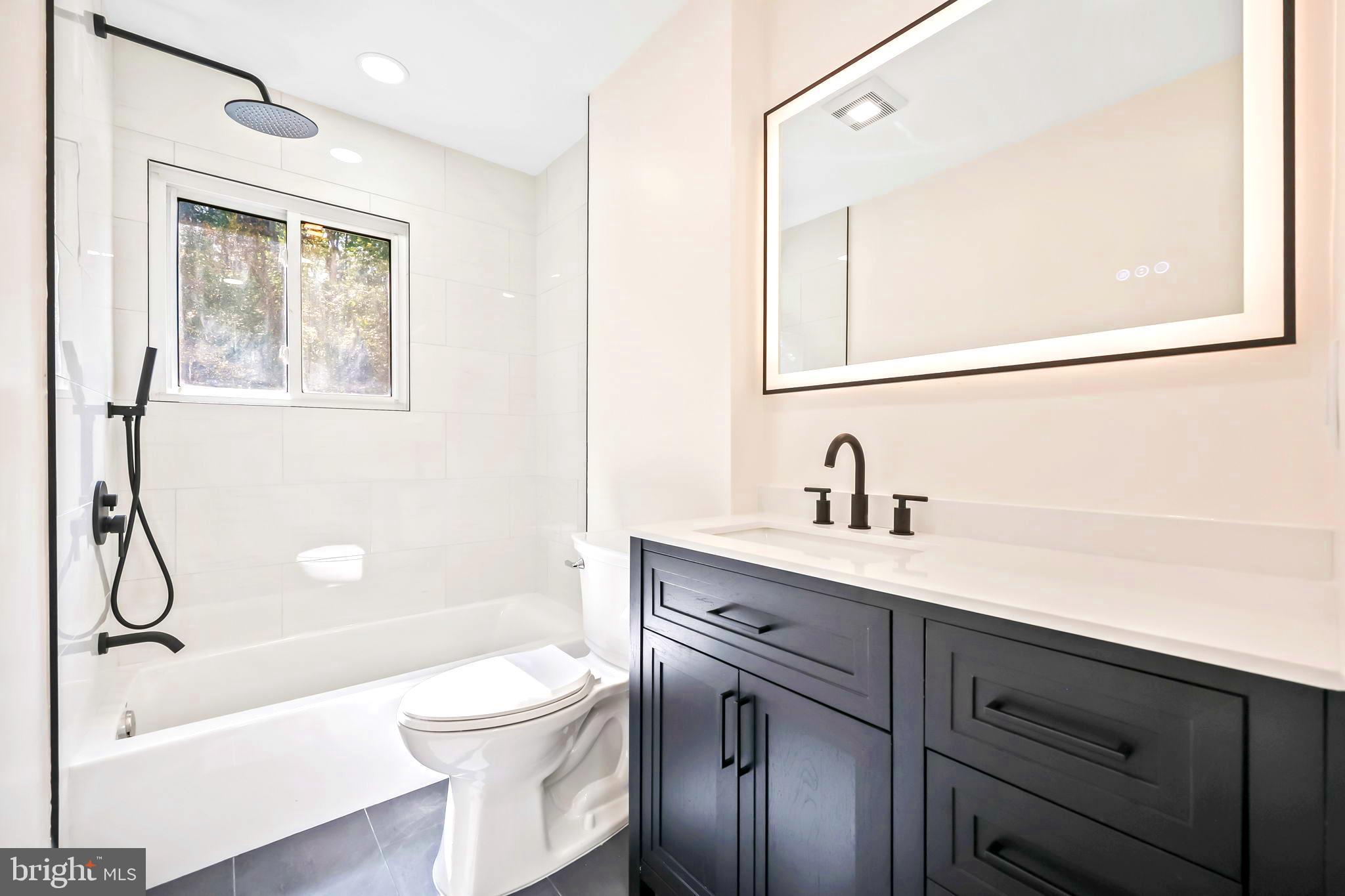 61 Argonne Avenue Hamilton, NJ 08620 - Photo 22 of 38 a bathroom with a toilet a sink a mirror a shower a vanity and window