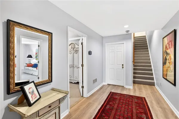 a view of a hallway to a livingroom with wooden floor and furniture