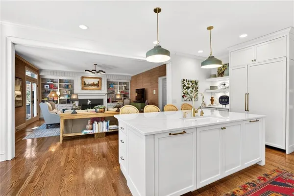 a living room with stainless steel appliances kitchen island granite countertop a sink dishwasher and white cabinets with wooden floor