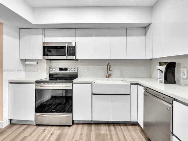 a kitchen with stainless steel appliances granite countertop a sink a stove and cabinets