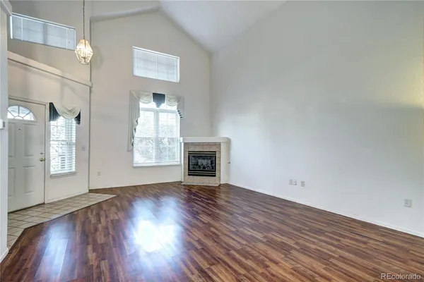 an empty room with wooden floor fireplace and windows