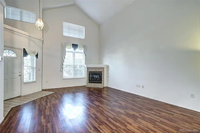 an empty room with wooden floor fireplace and windows