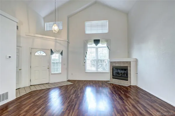 an empty room with wooden floor a fireplace and windows