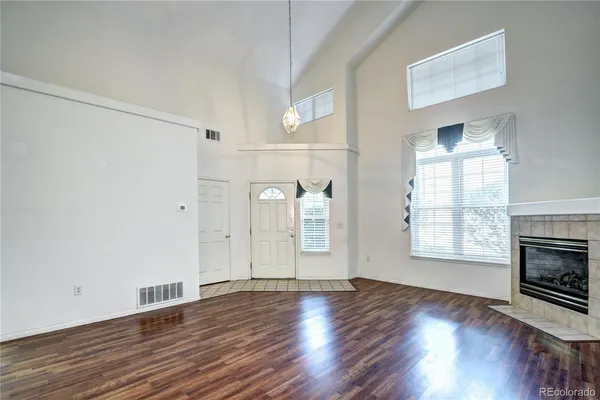 an empty room with wooden floor fireplace and windows