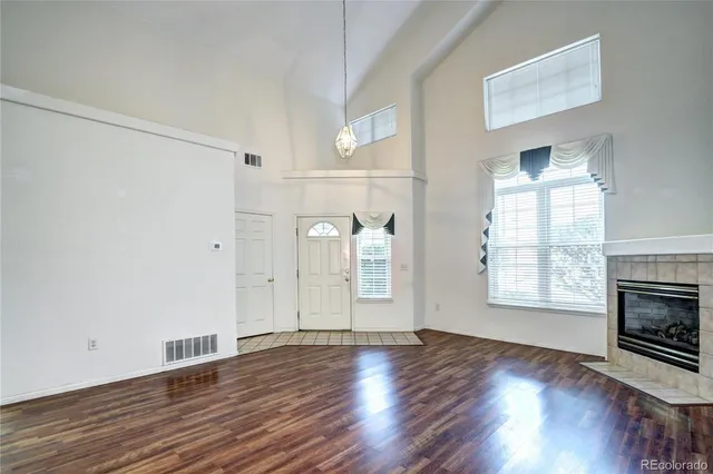 an empty room with wooden floor fireplace and windows