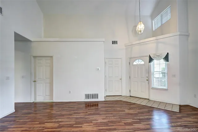 a view of an empty room with window and wooden floor