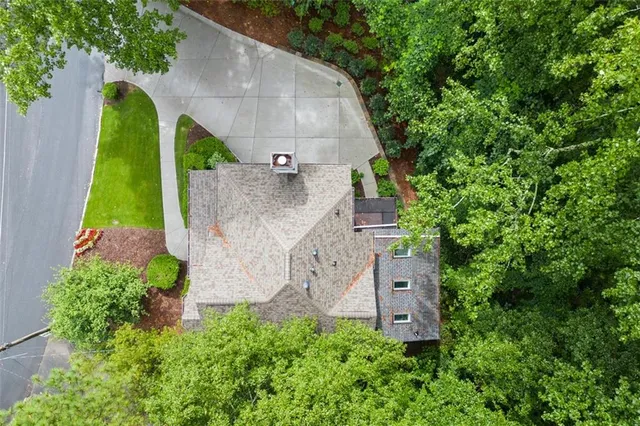 an aerial view of a house with garden space and trees all around