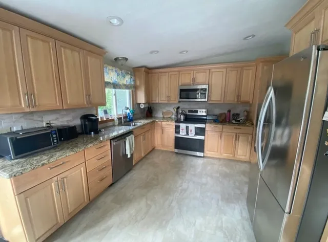 a kitchen with stainless steel appliances granite countertop a refrigerator a stove top oven a sink and dishwasher with wooden floor