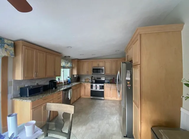 a kitchen with stainless steel appliances granite countertop a refrigerator sink and stove