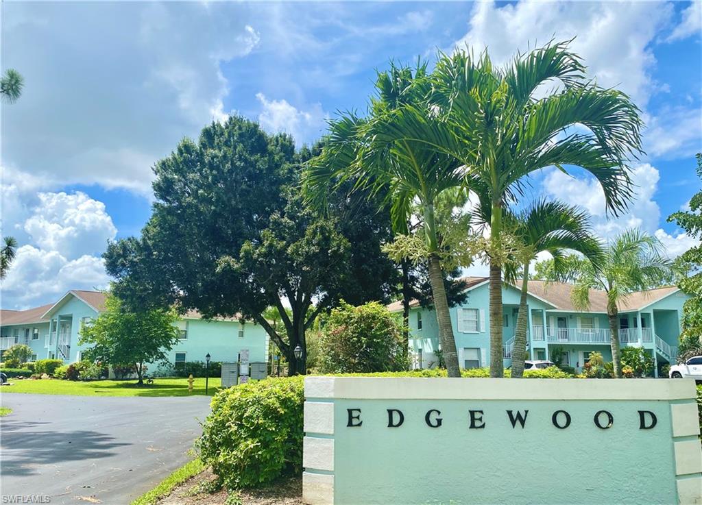 5735 Whitaker Road, Unit B201 Naples, FL 34112 - Photo 23 of 26 a view of yellow house with a yard and trees in front of it