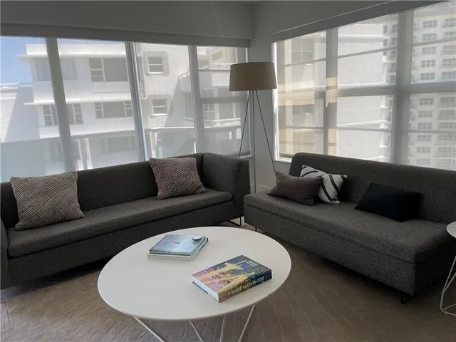 a living room with furniture a flat screen tv and a floor to ceiling window