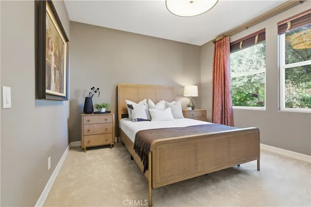 a large bed sitting in a bedroom next to a window and flowerpot