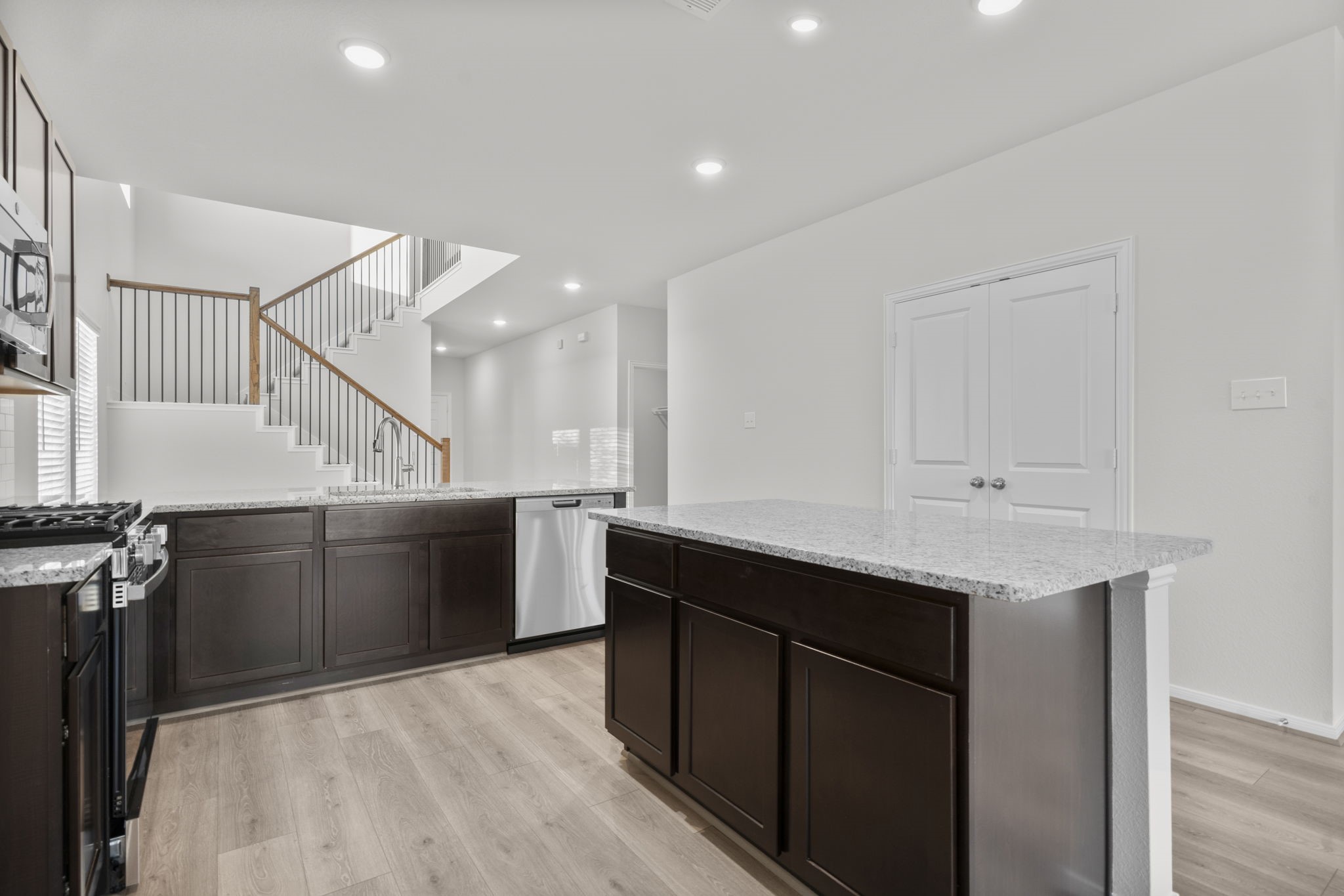 22223 Rome Breeze Drive Hockley, TX 77447 - Photo 9 of 46 Another perspective of the kitchen showcases the generous counter space and central island that connects seamlessly to the family room and staircase beyond. This elegant design encourages both functionality and togetherness in the heart of the home.