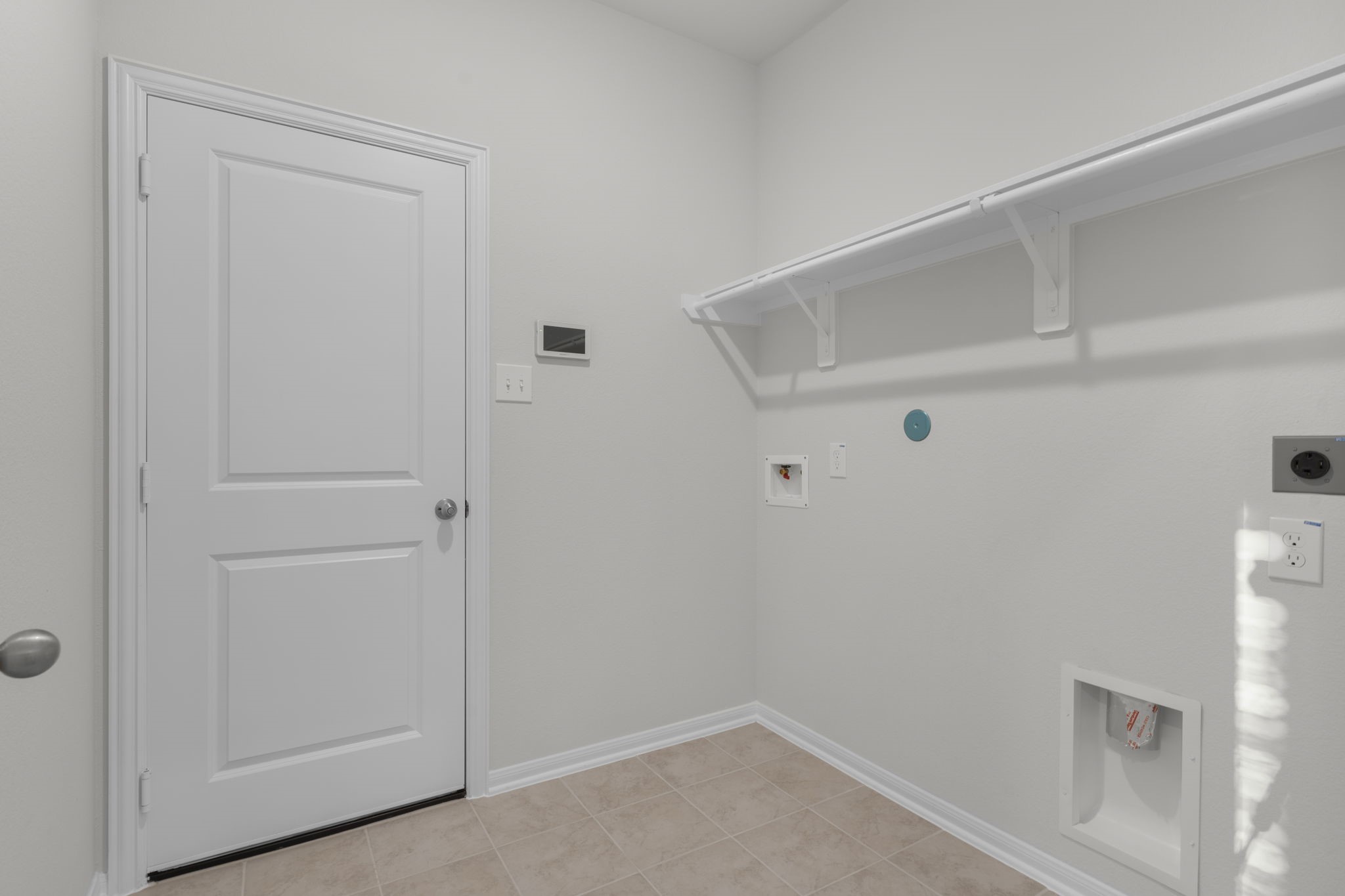 22223 Rome Breeze Drive Hockley, TX 77447 - Photo 10 of 46 The utility room is conveniently located on the first floor and offers space for a full-size washer and dryer along with built-in shelving for added storage. Its practical design keeps laundry day simple and organized while maintaining a clean, modern look.