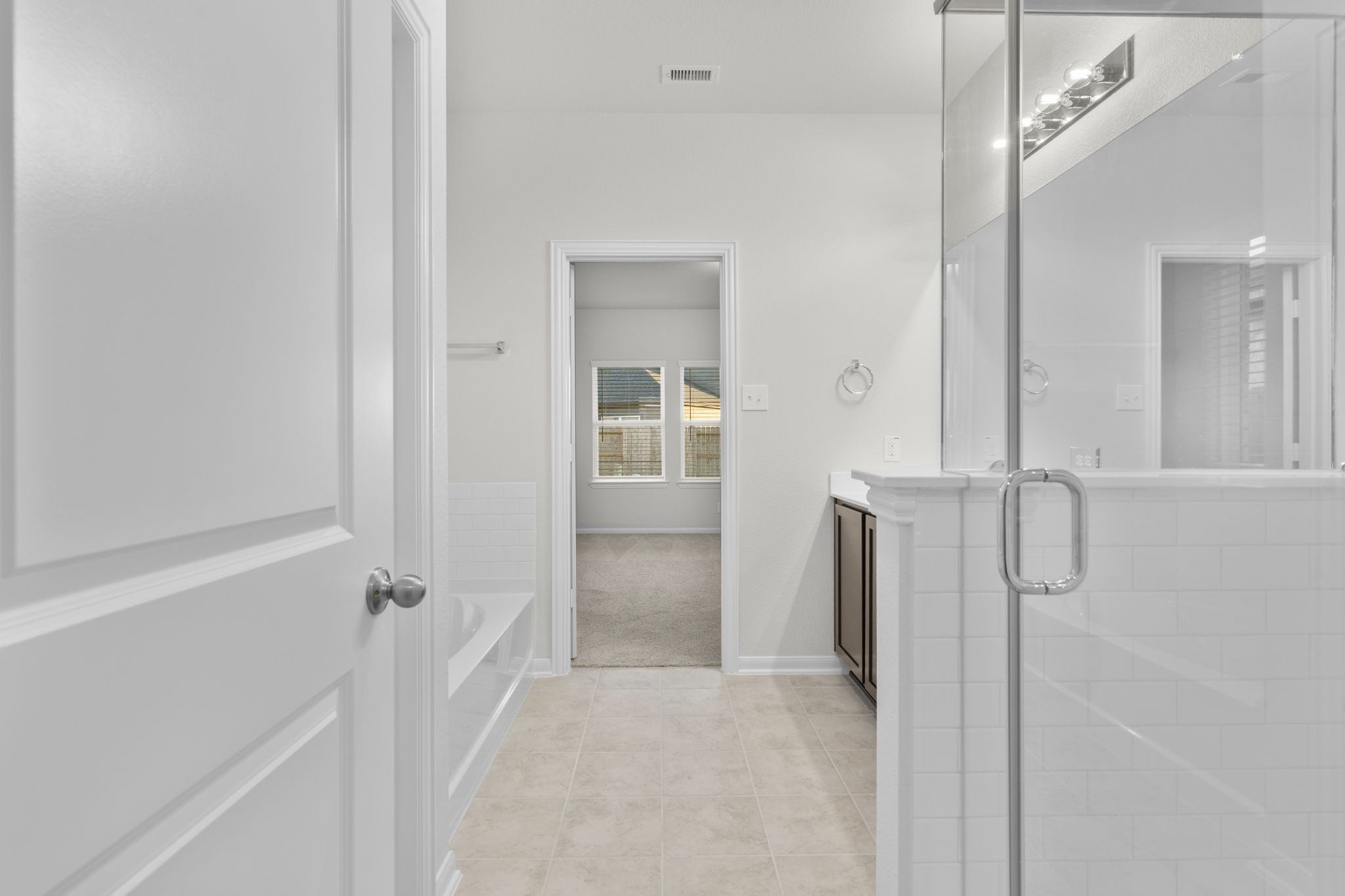 22223 Rome Breeze Drive Hockley, TX 77447 - Photo 17 of 46 A view from the primary suite bathroom hallway highlights the dual vanity and generous counter space leading to the primary suite. This layout enhances functionality and flow, offering a private, spa-like atmosphere.
