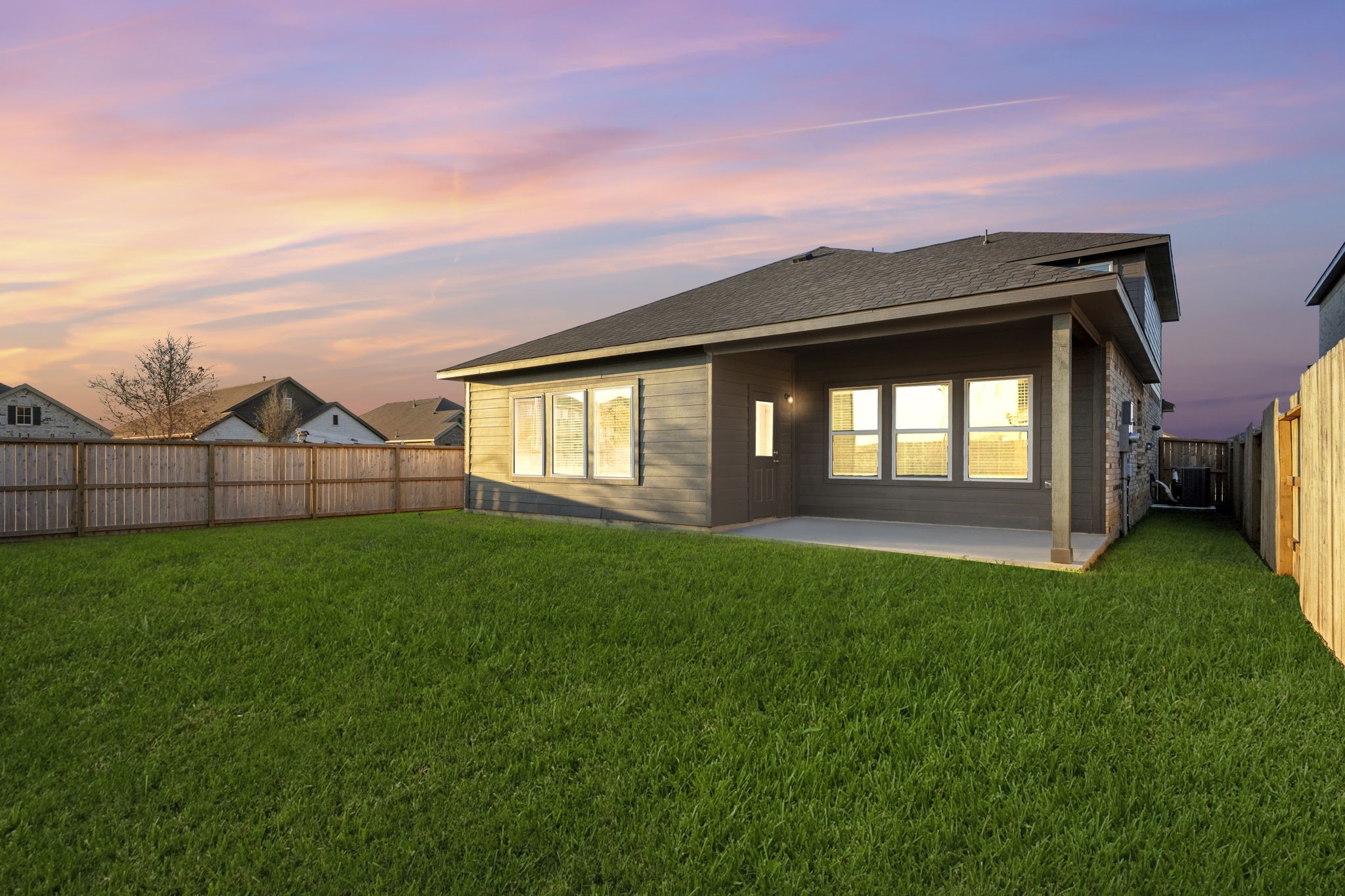22223 Rome Breeze Drive Hockley, TX 77447 - Photo 31 of 46 Another twilight view showcases the spacious backyard and extended covered patio, ideal for relaxing evenings or entertaining under the stars. The large windows across the back of the home reflect the serene beauty of sunset skies.