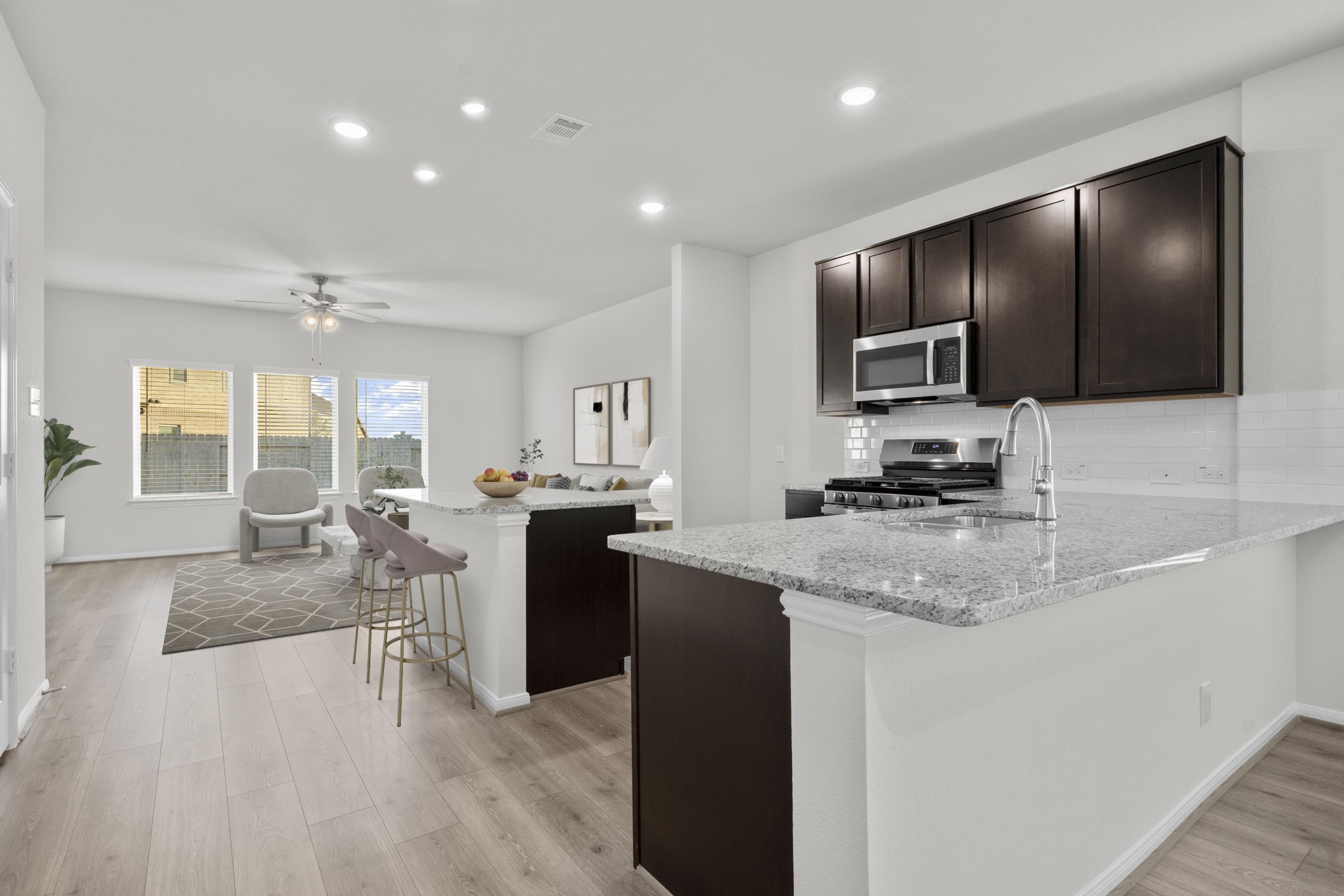 22223 Rome Breeze Drive Hockley, TX 77447 - Photo 4 of 46 The open-concept kitchen flows effortlessly into the family and dining areas, creating a bright and airy layout perfect for entertaining. Enjoy the combination of dark cabinetry, granite countertops, and sleek stainless-steel appliances that give this space a polished, modern feel.