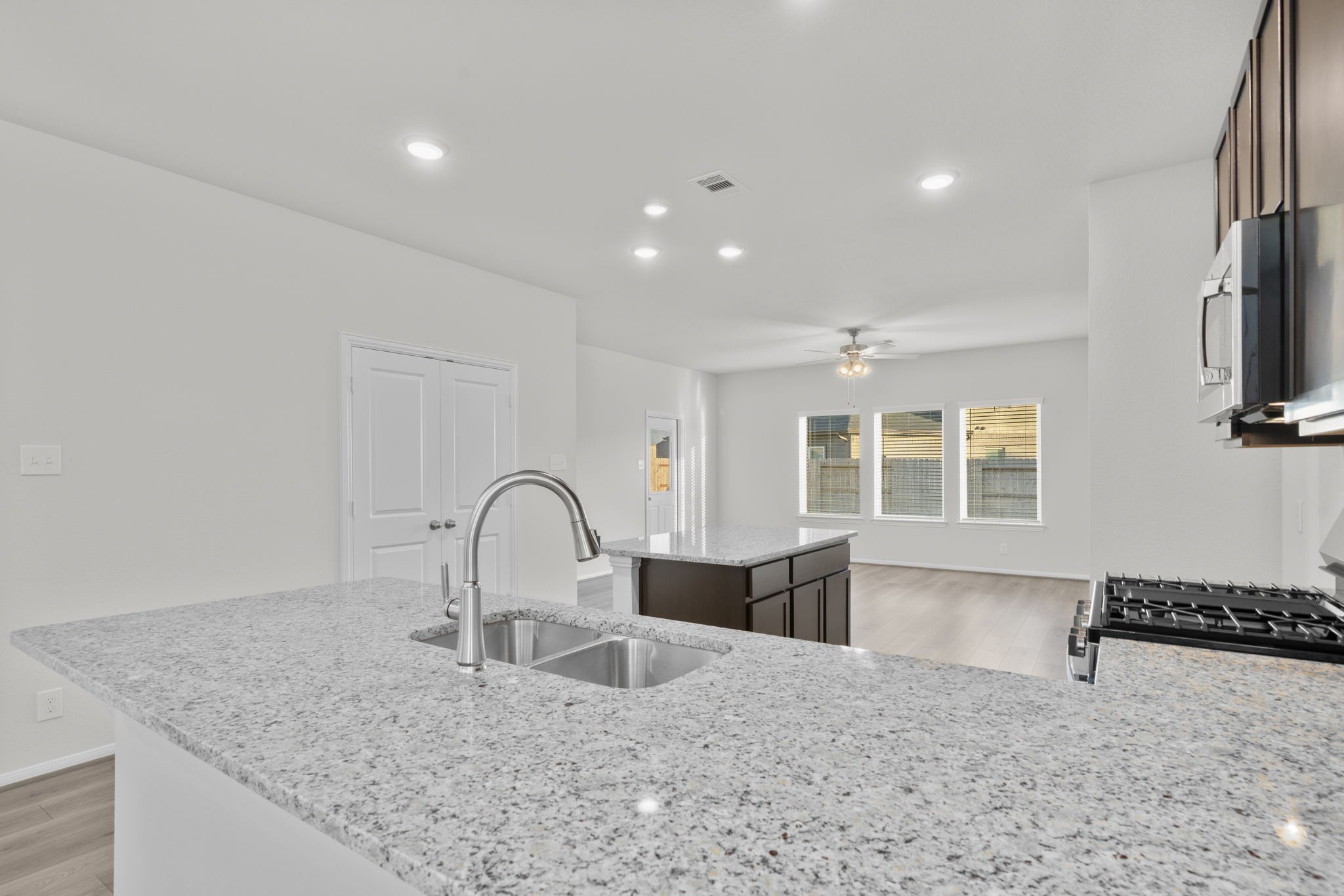 22223 Rome Breeze Drive Hockley, TX 77447 - Photo 5 of 46 This view of the kitchen highlights the expansive island with a deep undermount stainless sink and seating space ideal for casual dining or conversation. Recessed lighting and large windows fill the home with warmth and natural light from every angle.