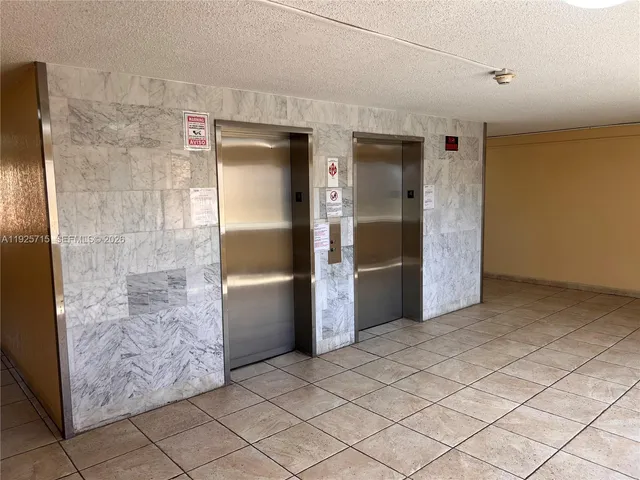 a view of a refrigerator in kitchen and an empty room in wooden floor