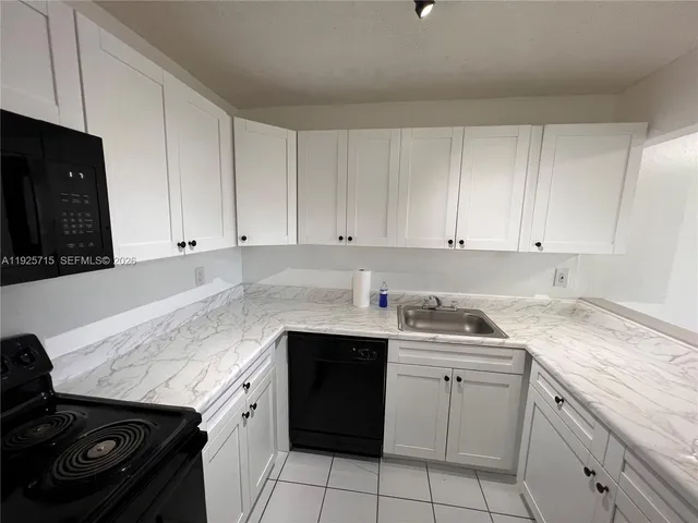 a kitchen with granite countertop white cabinets and black appliances