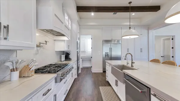 a large white kitchen with a large window and stainless steel appliances