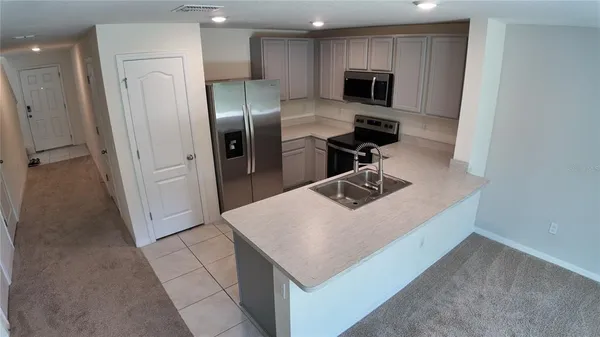 a kitchen with a refrigerator a microwave a sink and cabinets