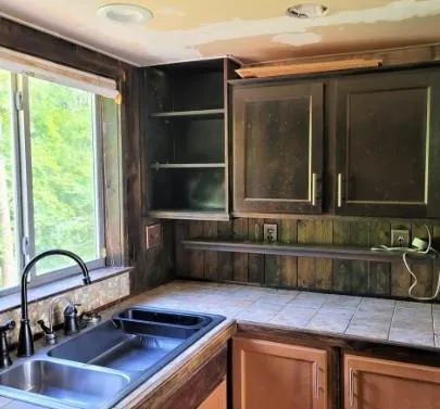a kitchen with a sink and a stove with wooden floor
