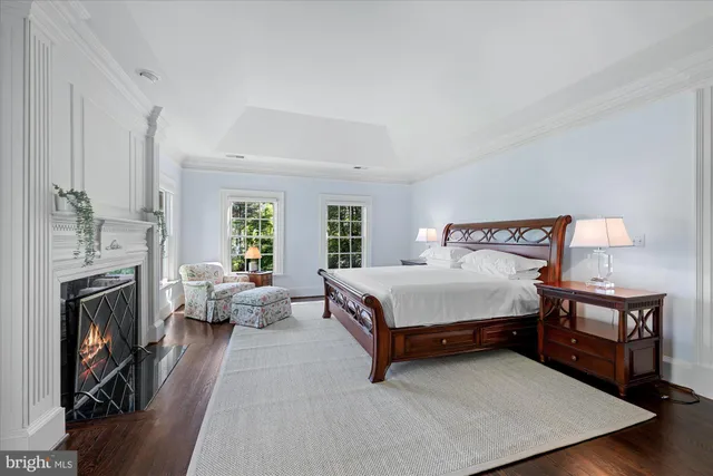 a bed sitting in a spacious bedroom next to a window with a fireplace