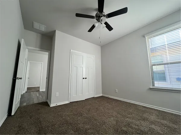 an empty room with a window and a fan
