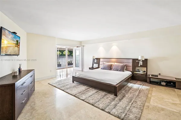a bedroom with a large bed and a flat tv screen on dresser