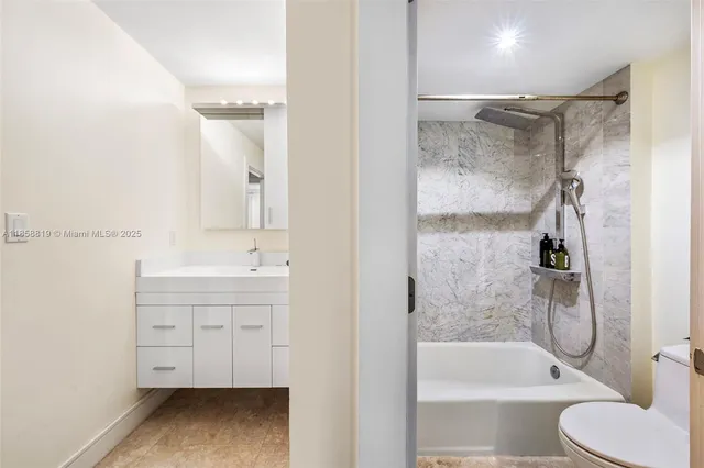 a bathroom with a tub shower sink vanity and toilet