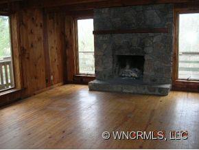 1448 Silvers Mill Road Marshall, NC 28753 - Photo 3 of 12 an empty room with wooden floor and a fireplace