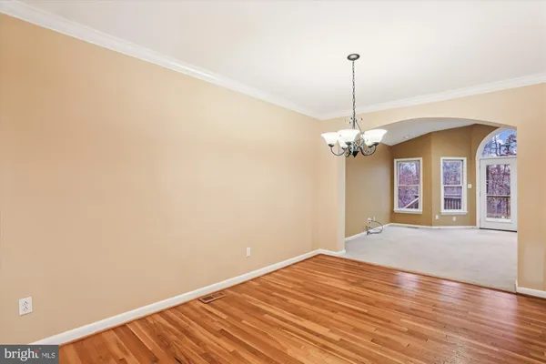 a view of a room with wooden floor chandelier and a window