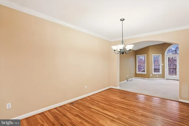 a view of a room with wooden floor chandelier and a window