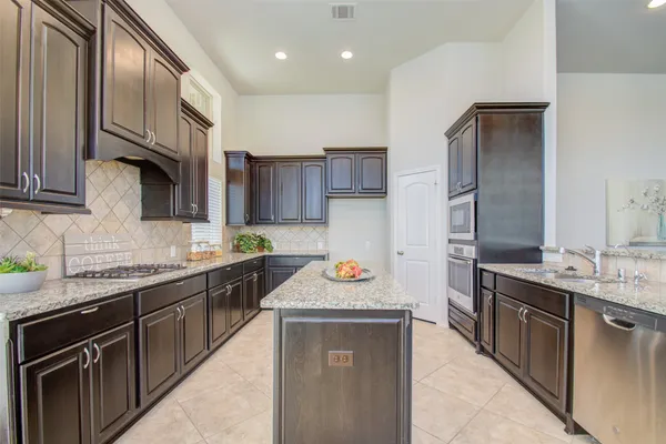 a kitchen with stainless steel appliances granite countertop a stove top oven a sink dishwasher a refrigerator and a cabinets with wooden floor
