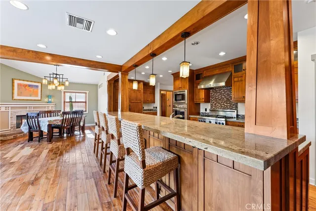 a dining hall with stainless steel appliances granite countertop a stove and a view of living room