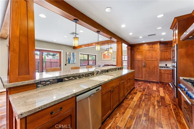 a large kitchen with stainless steel appliances a large counter top a stove a sink and a refrigerator