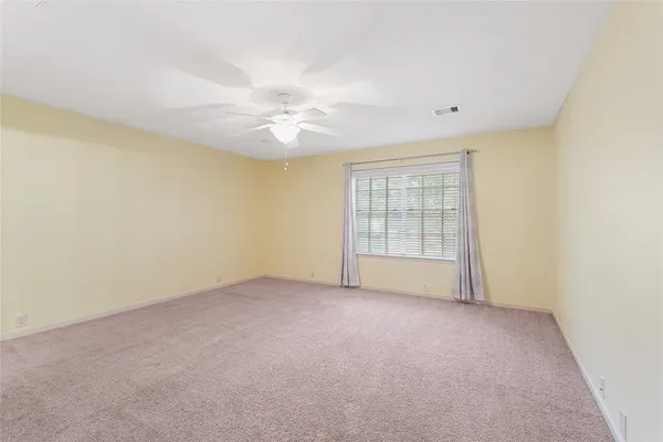an empty room with windows and fan