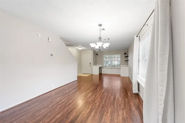 a view of a livingroom with wooden floor and a kitchen