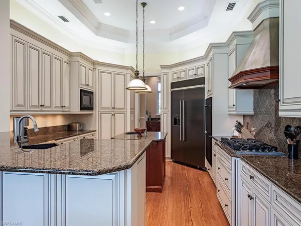 a kitchen with stainless steel appliances granite countertop a refrigerator a stove and a sink