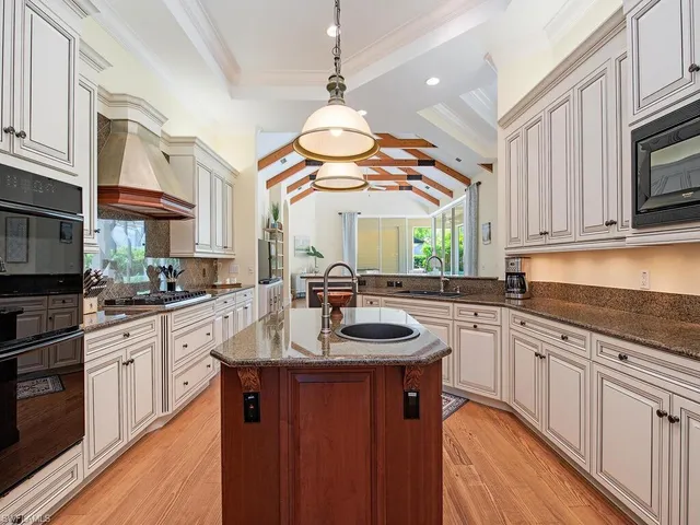 a kitchen with kitchen island granite countertop a sink a counter top space appliances and cabinets