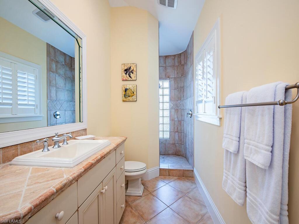 194 4th Avenue North Naples, FL 34102 - Photo 29 of 37 a bathroom with a sink a toilet a mirror and shower