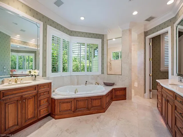 a spacious bathroom with a tub sink and mirror