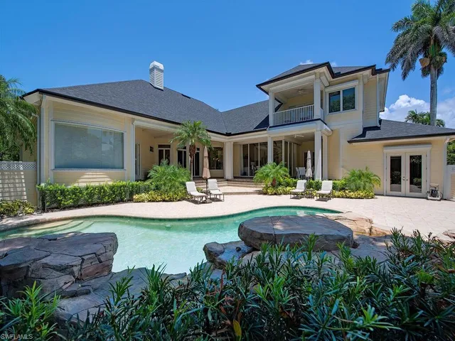 a front view of a house with swimming pool and porch with furniture